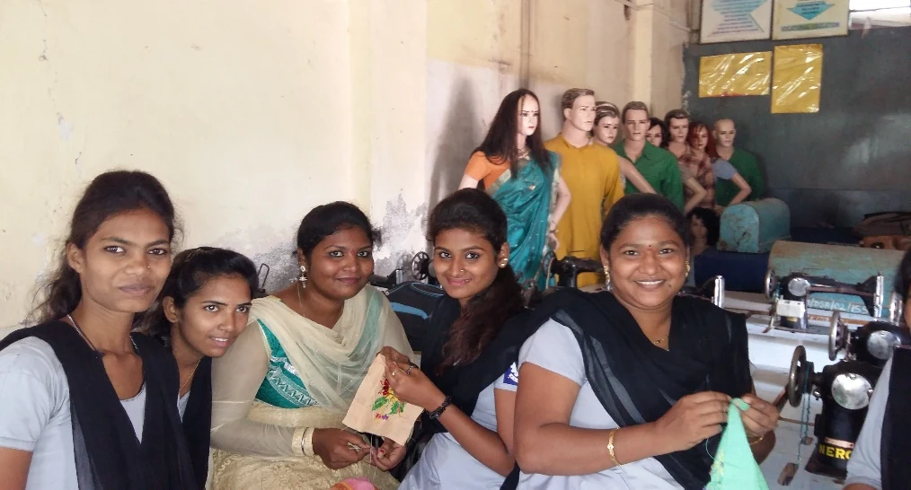 Young women in CDROME fashion and beauty training programme, smiling with sewing machines